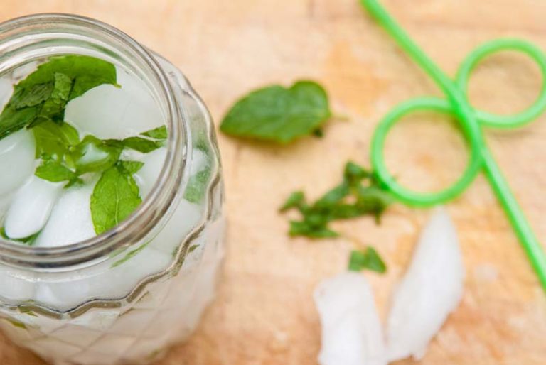 Stevia leaves in drink in clear glass with green straw on the side