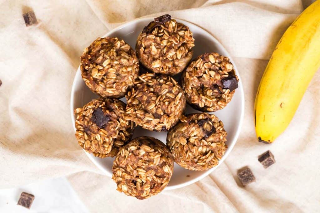 white bowl with 7 banana oatmeal bites with a banana next to it